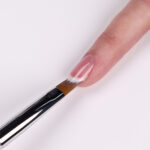 Pensel som påfører en hvit linje for fransk manikyr